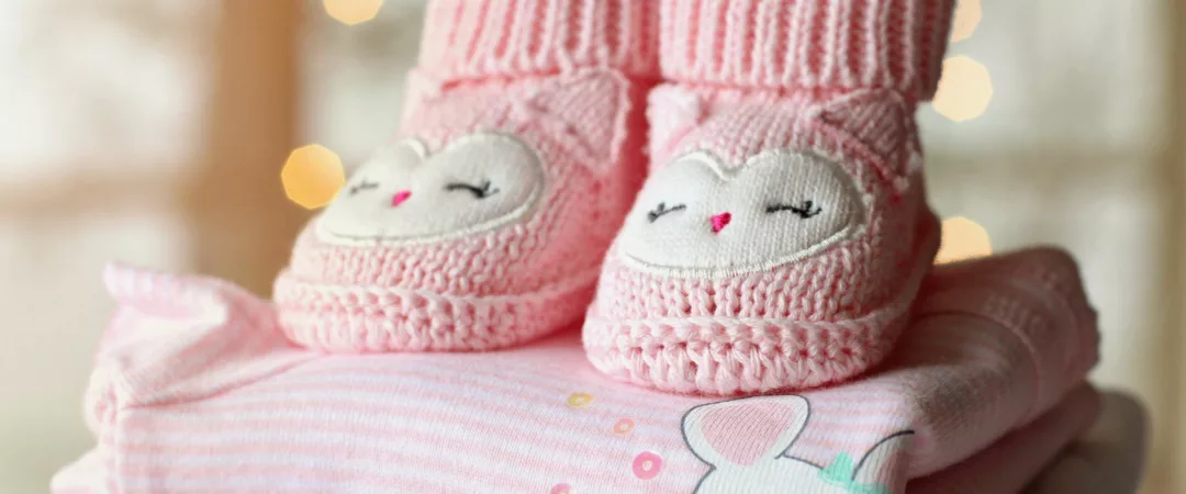Chaussons roses de bébé sur des vêtements pliés